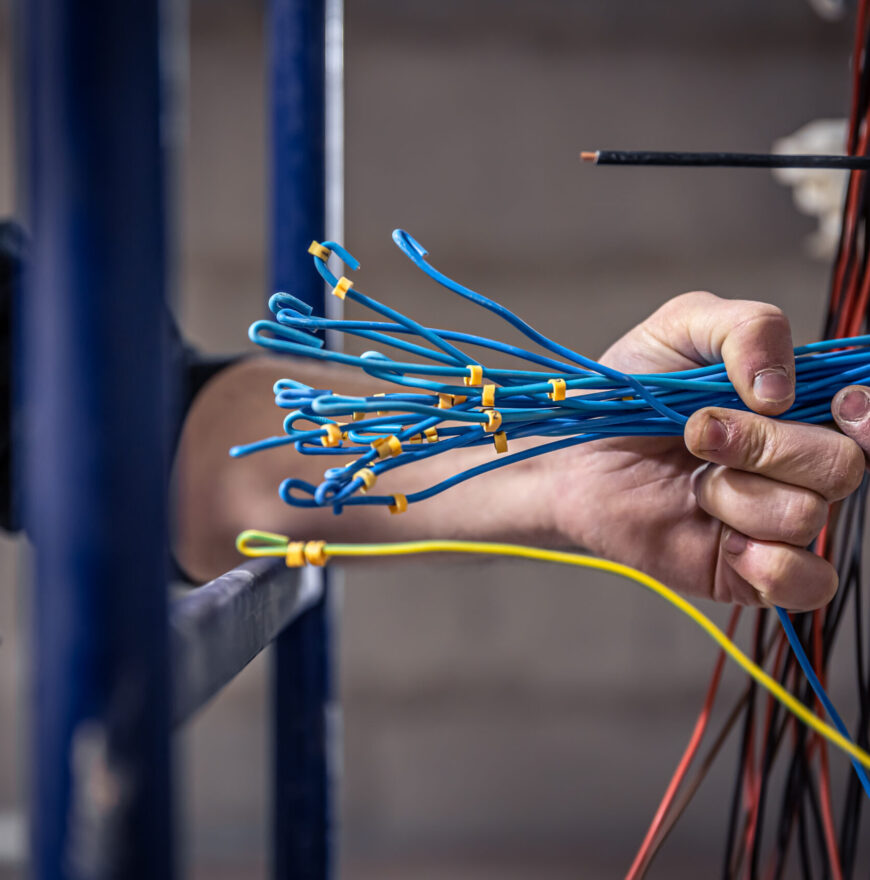 A construction electrician cuts a voltage cable during a repair, close up.