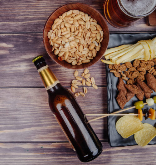 top view of varied beer snacks with a bottle of beer on rustic background with copy space top view of varied beer snacks with a bottle of beer on rustic background with copy space